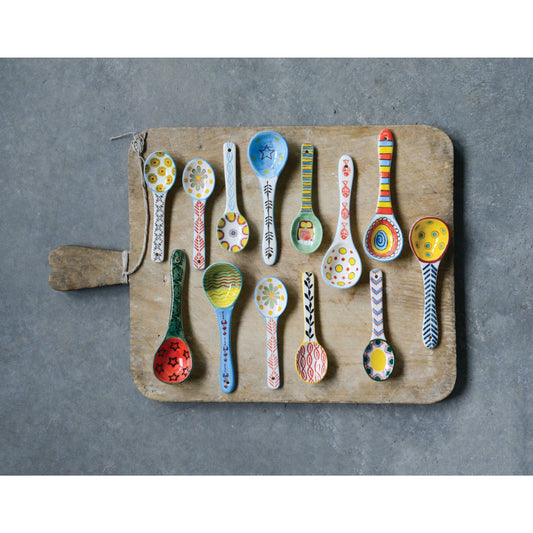 Hand-painted stoneware spoon set with colorful patterns on wooden board