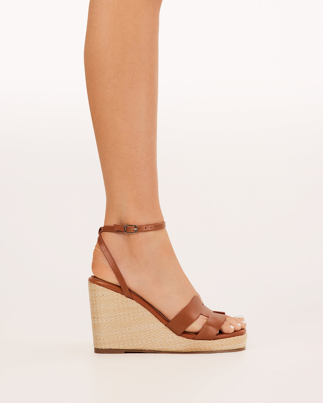 Tan wedge sandals with ankle buckle strap and open toe, woven textured midsole