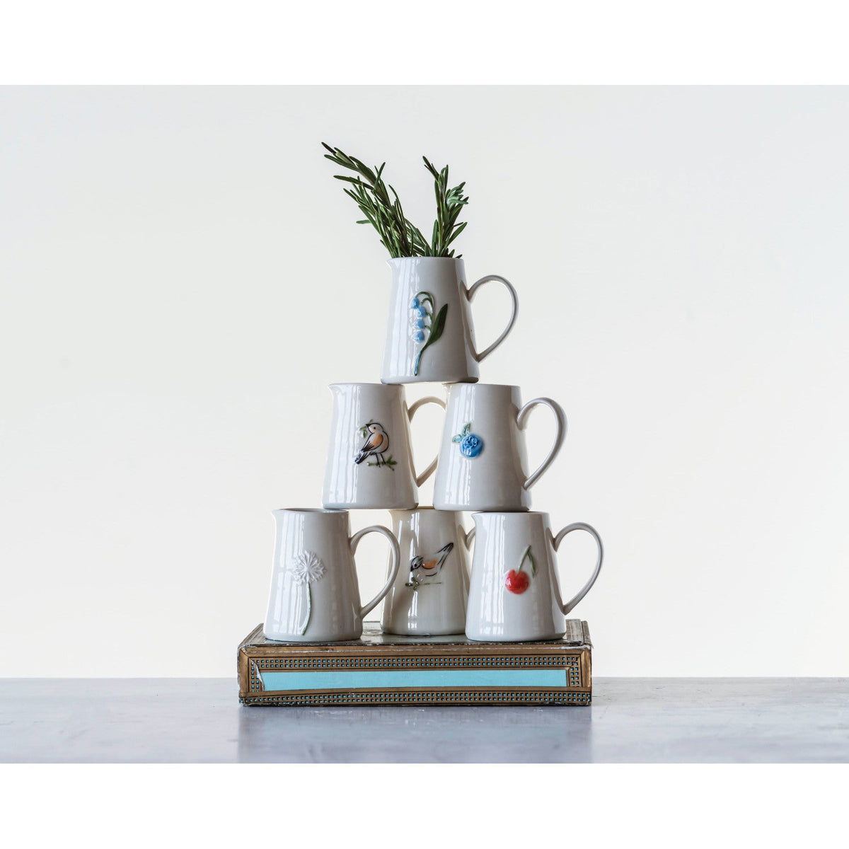 Mini ceramic creamer cups stacked on a decorative tray, blue flower and bird designs
