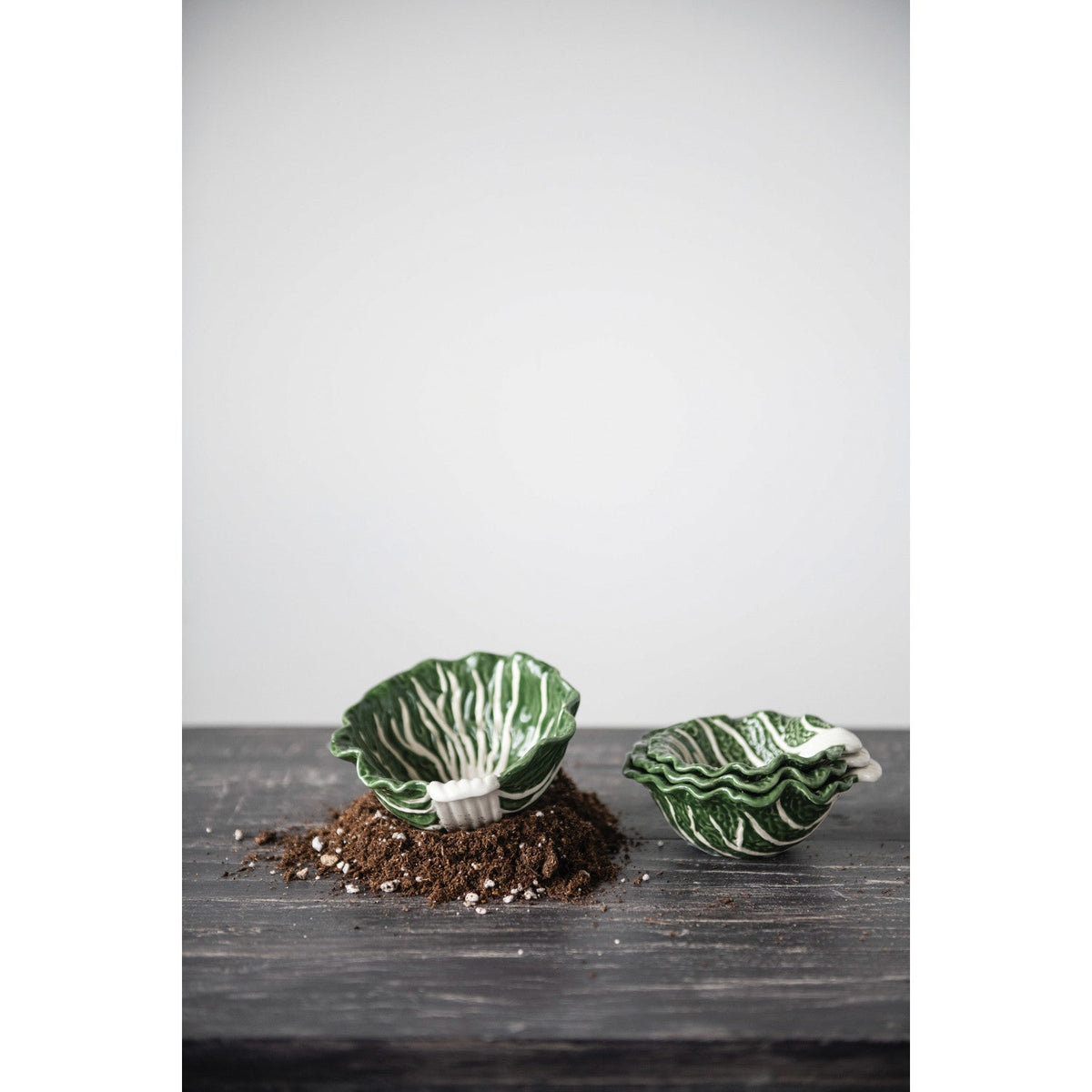 Two small cabbage-shaped nesting bowls, glossy green with white veining.