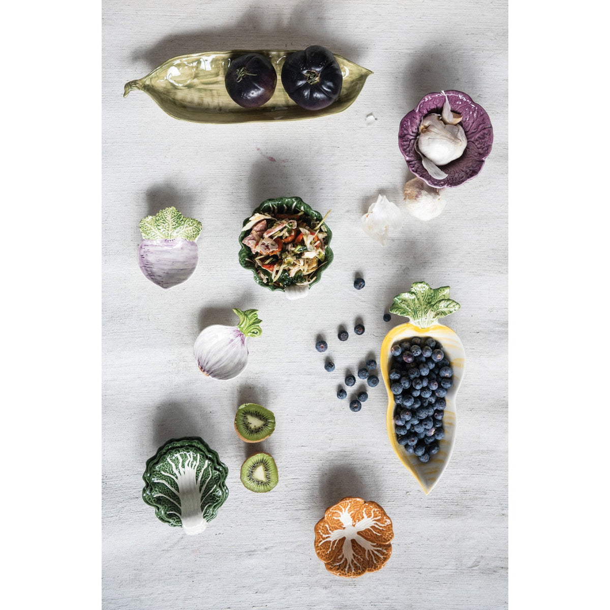 Assorted cabbage-shaped nesting bowls, glossy green and white ceramic pieces.