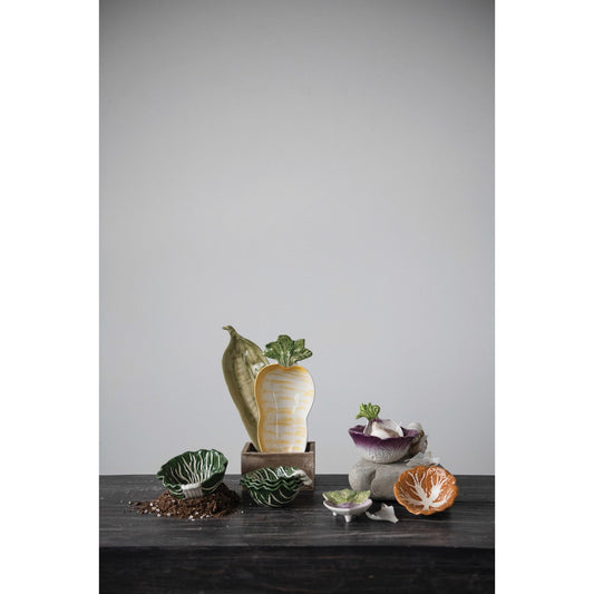 Cabbage-shaped nesting bowls set, glossy green and white ceramic on a dark surface.
