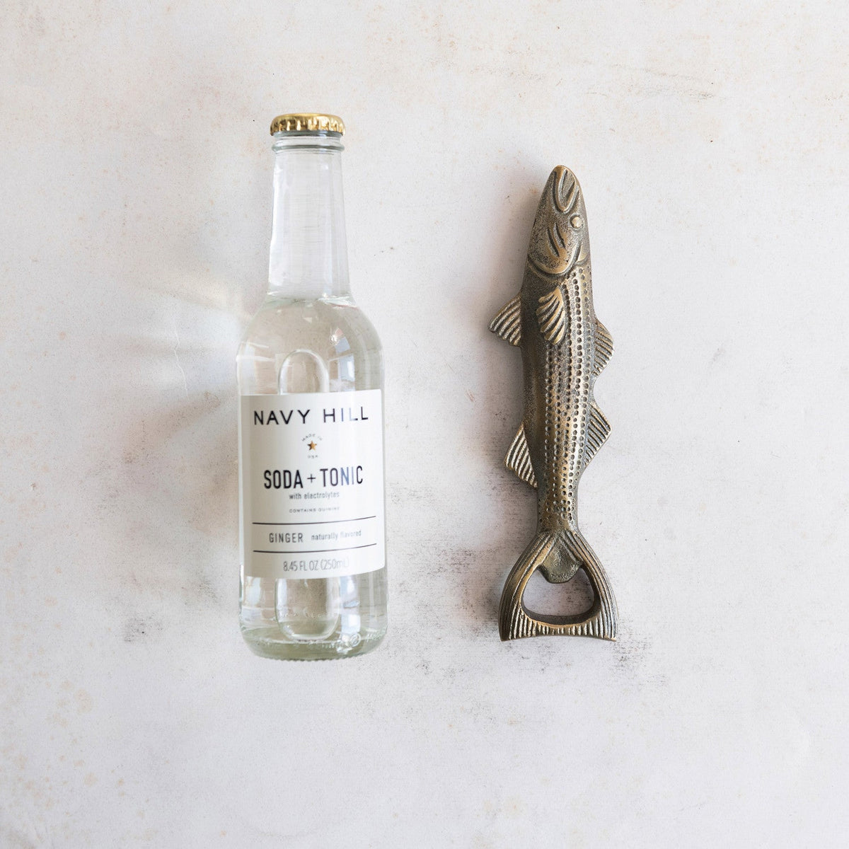 Antique gold fish bottle opener with textured scales and ring-style handle