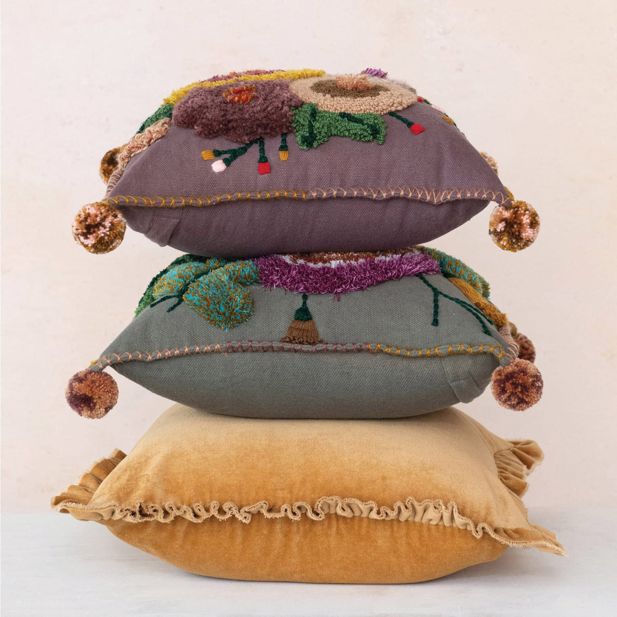 Stacked pillows featuring a mustard square velvet pillow with ruffled trim