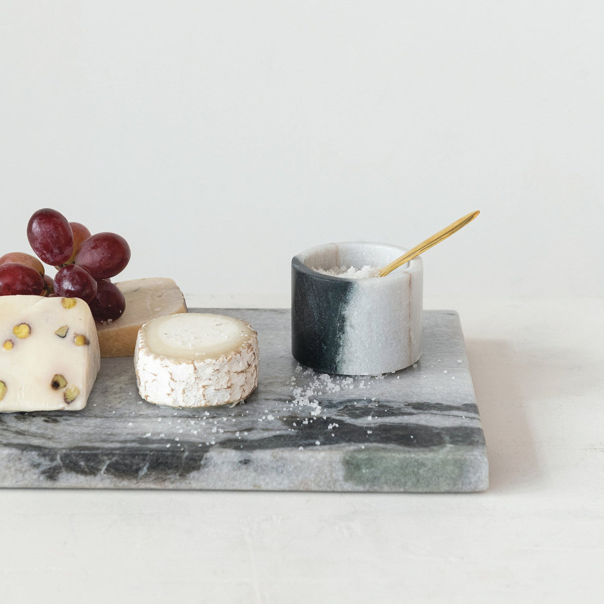 Marble salt cellar cup and brass spoon on rectangular gray stone base