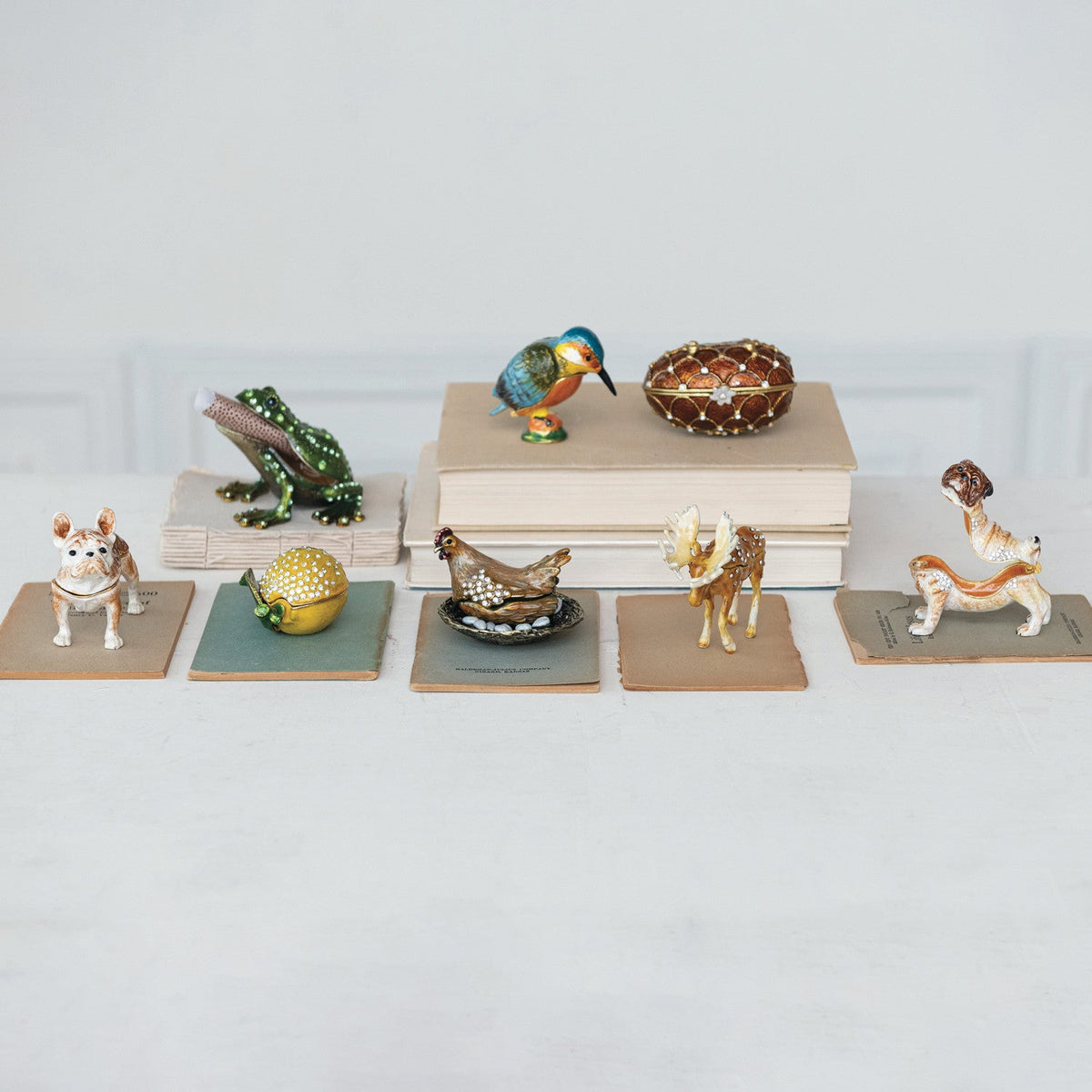 Kingfisher-shaped enamel metal trinket box on shelf among assorted ornaments