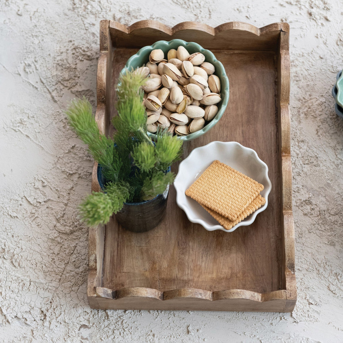 Mango wood scalloped-edge tray holding a bowl with nuts and small decorative greenery.