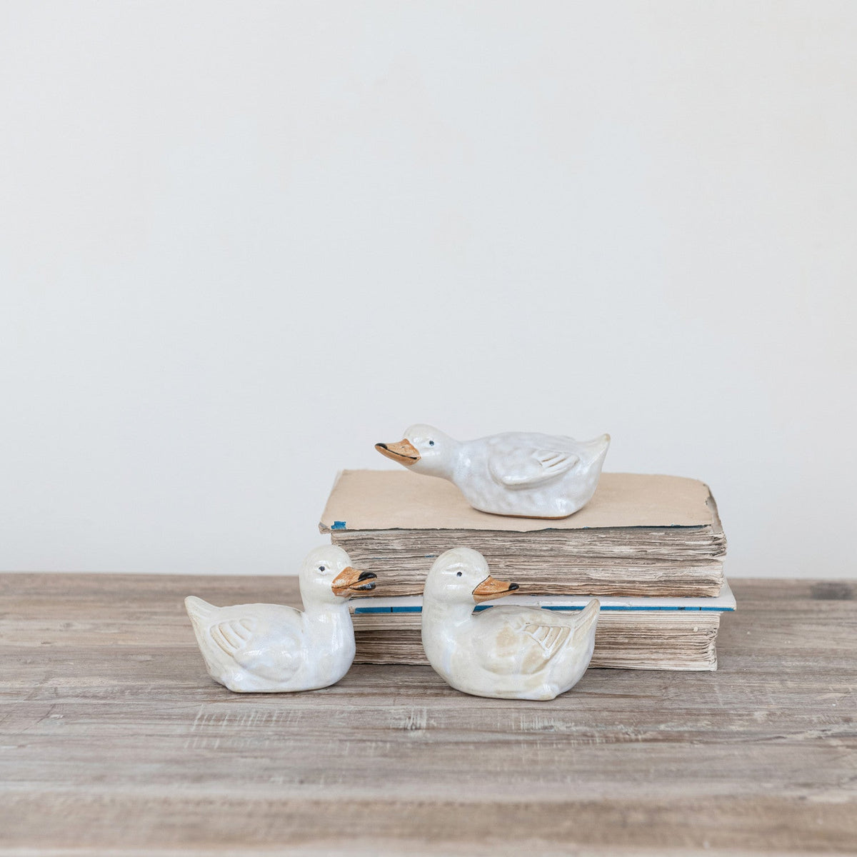 Set of three ceramic duckling figurines, pale white glaze with orange beaks and feet