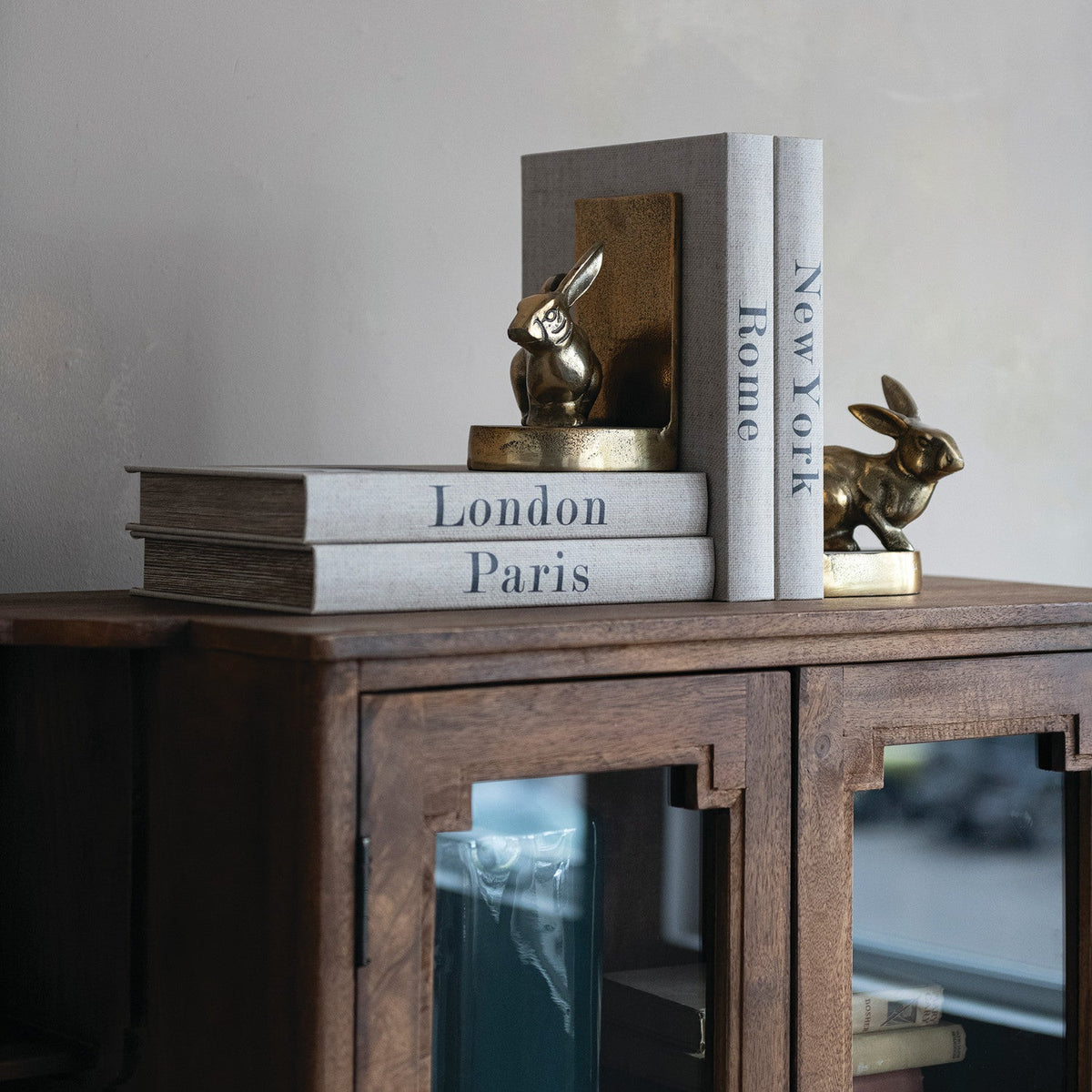 Antique gold rabbit bookends between book spines on a sideboard