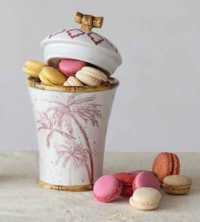 Hand-painted ceramic canister with palm trees, gold rim, open lid and colorful macarons