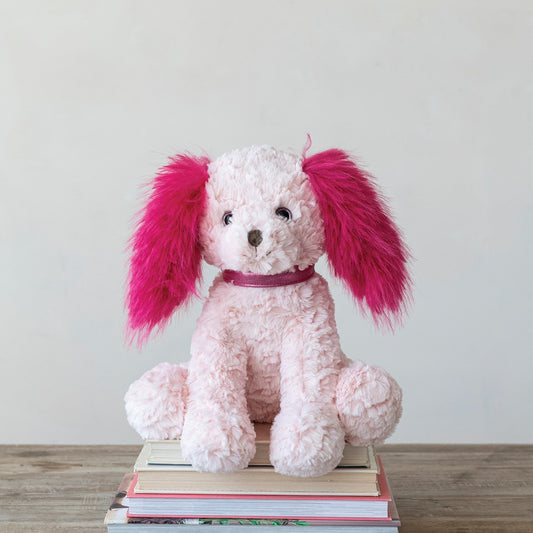 Pink and fuchsia plush dog with bow collar, sitting on books