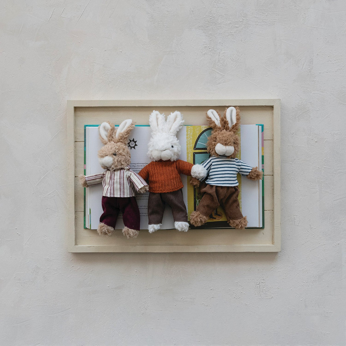 Set of three plush bunny toys in outfits displayed inside a framed shadowbox