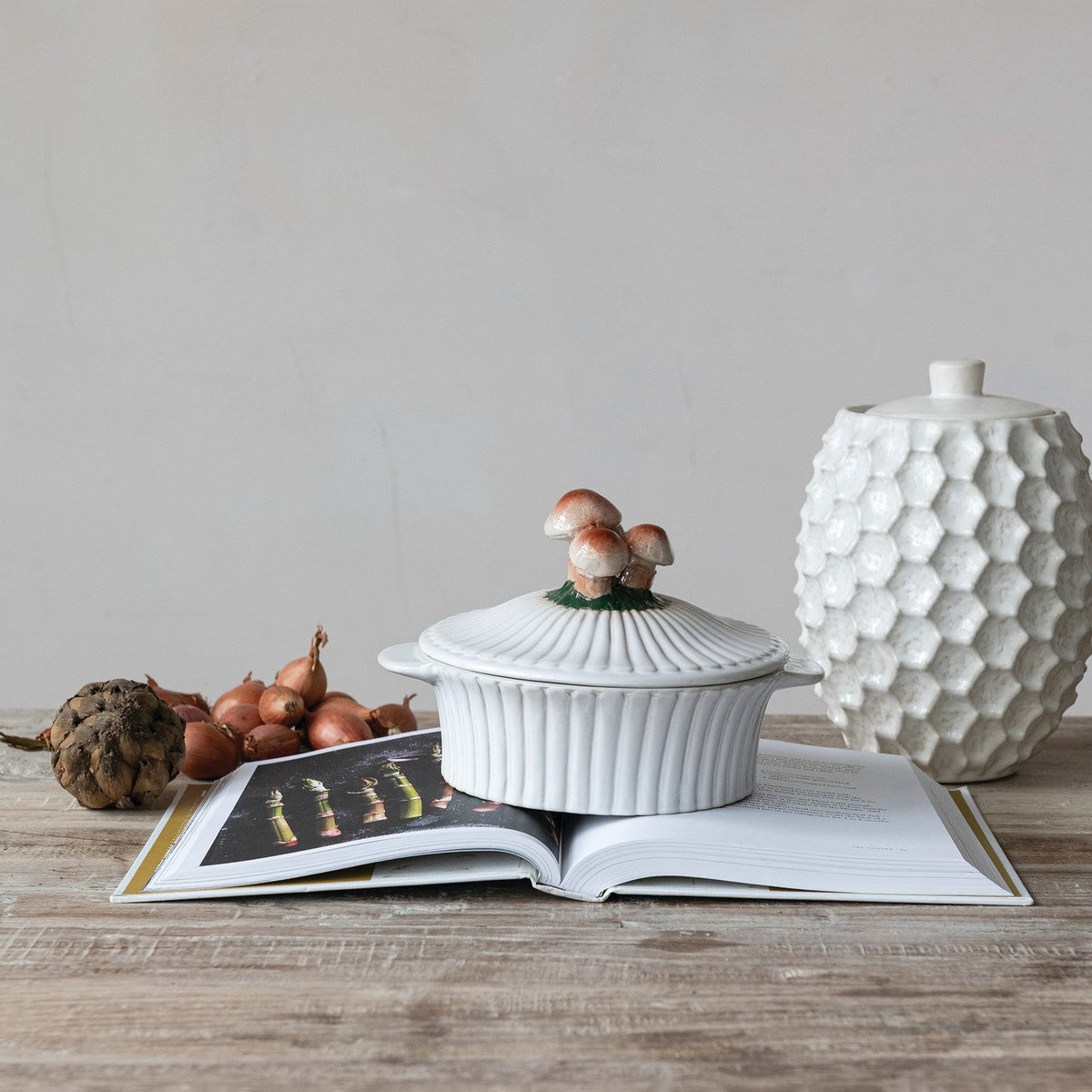 White ceramic fluted baking dish with mushroom lid on wooden table