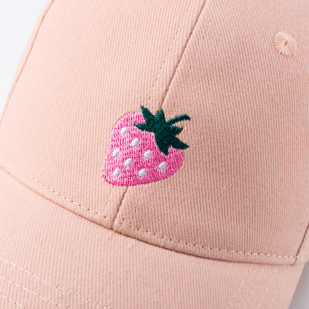 Close-up of embroidered strawberry on pink cotton cap