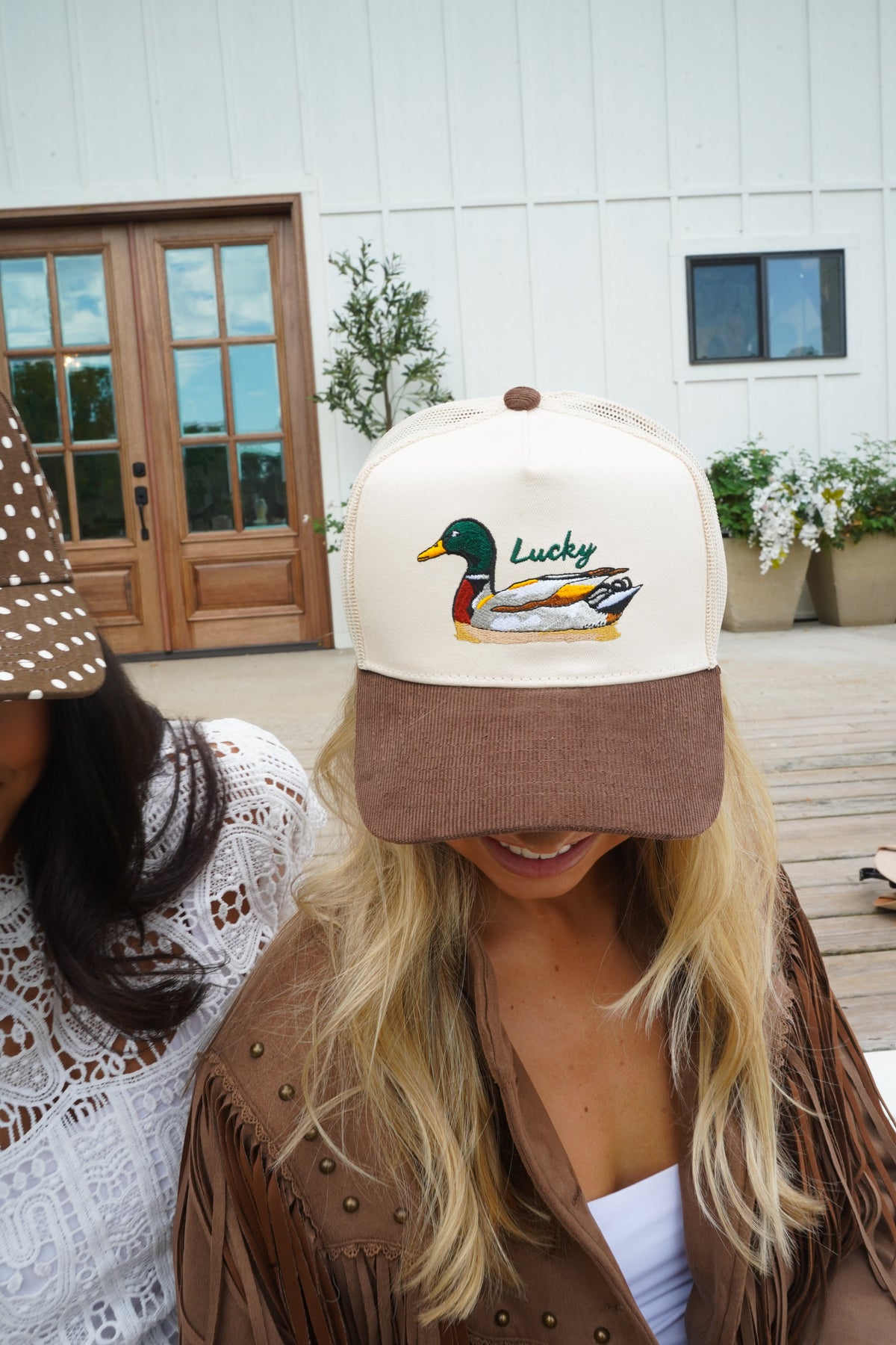 Cream and brown trucker hat featuring a duck “Lucky” logo on the front.