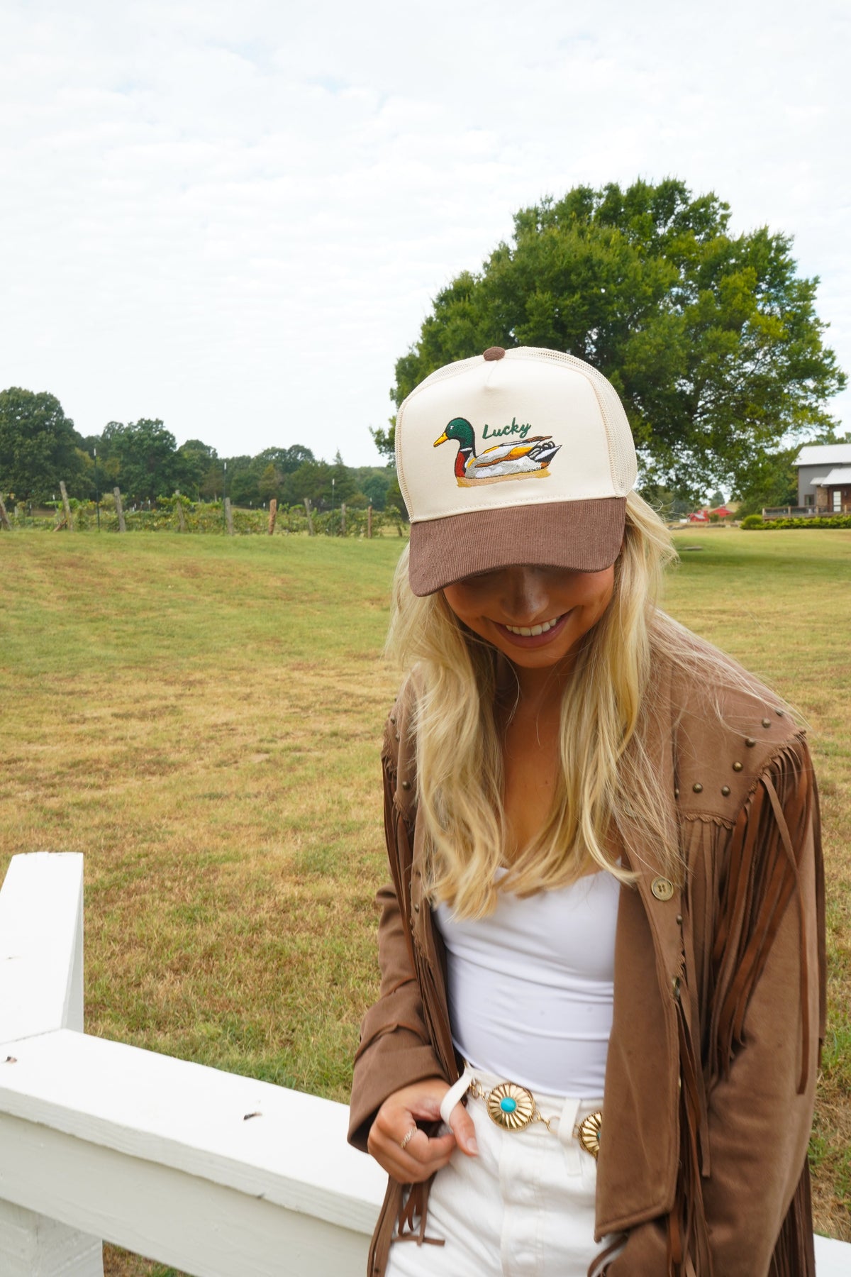 Cream trucker hat with brown corduroy brim and embroidered duck “Lucky” emblem.