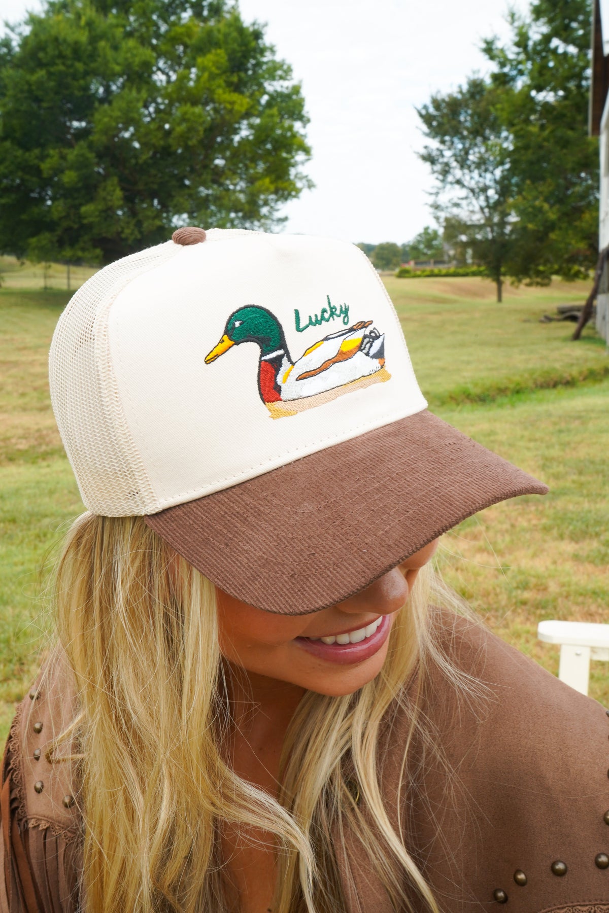 Close-up of white-and-brown trucker hat front with duck logo patch.