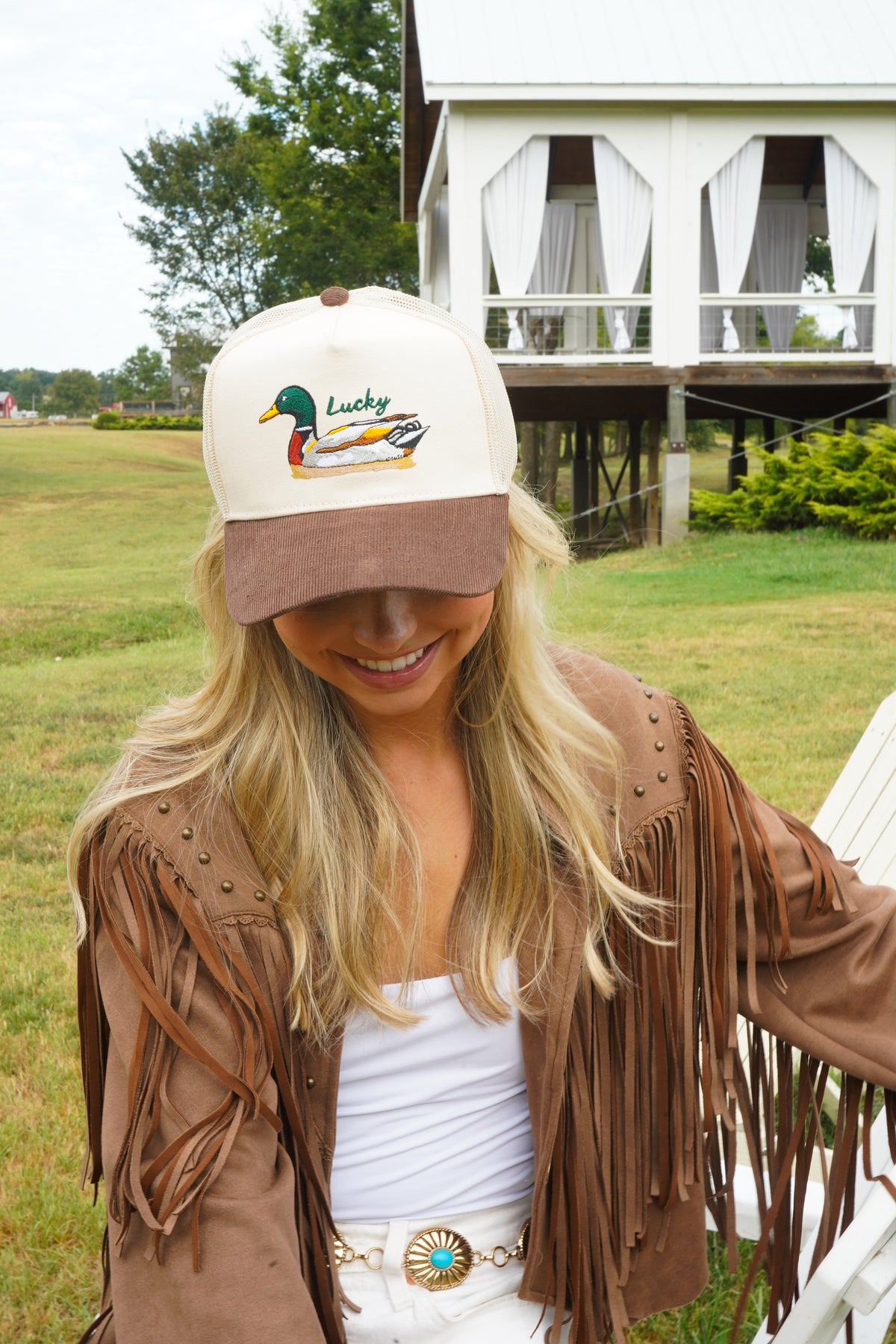 Woman in cream-and-brown trucker hat with Lucky duck front patch and brown brim