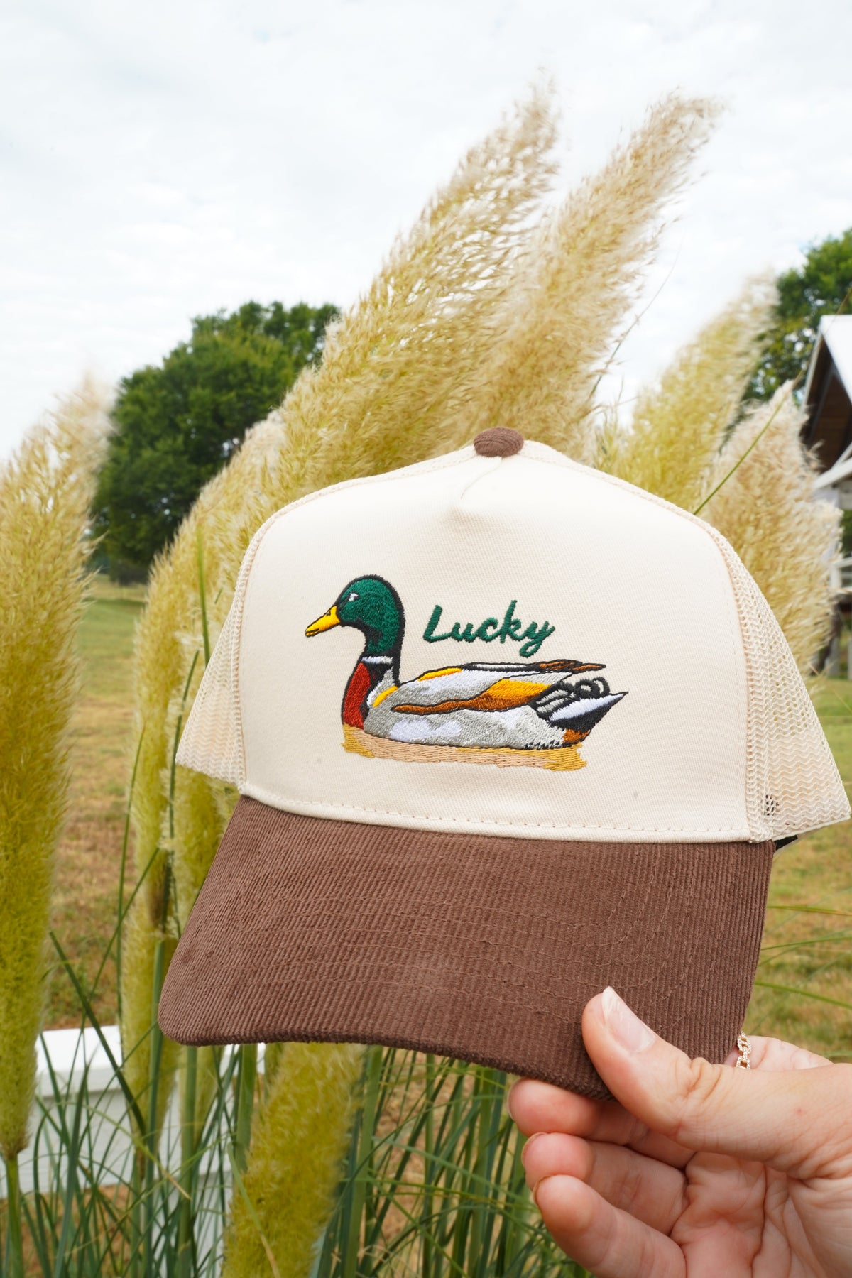 Brown corduroy trucker hat with cream mesh panels and Lucky duck front graphic