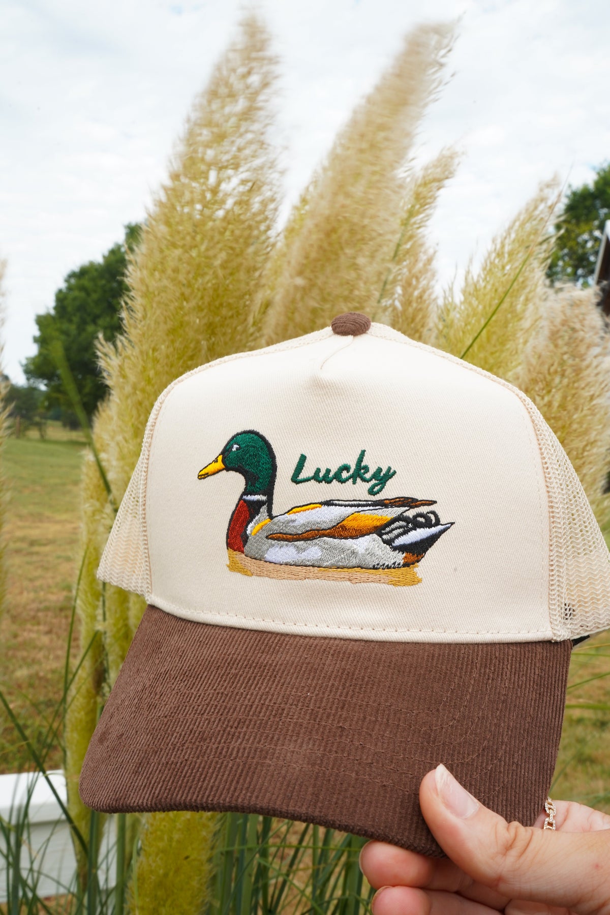 Trucker hat with cream mesh front and brown corduroy brim, featuring Lucky duck patch