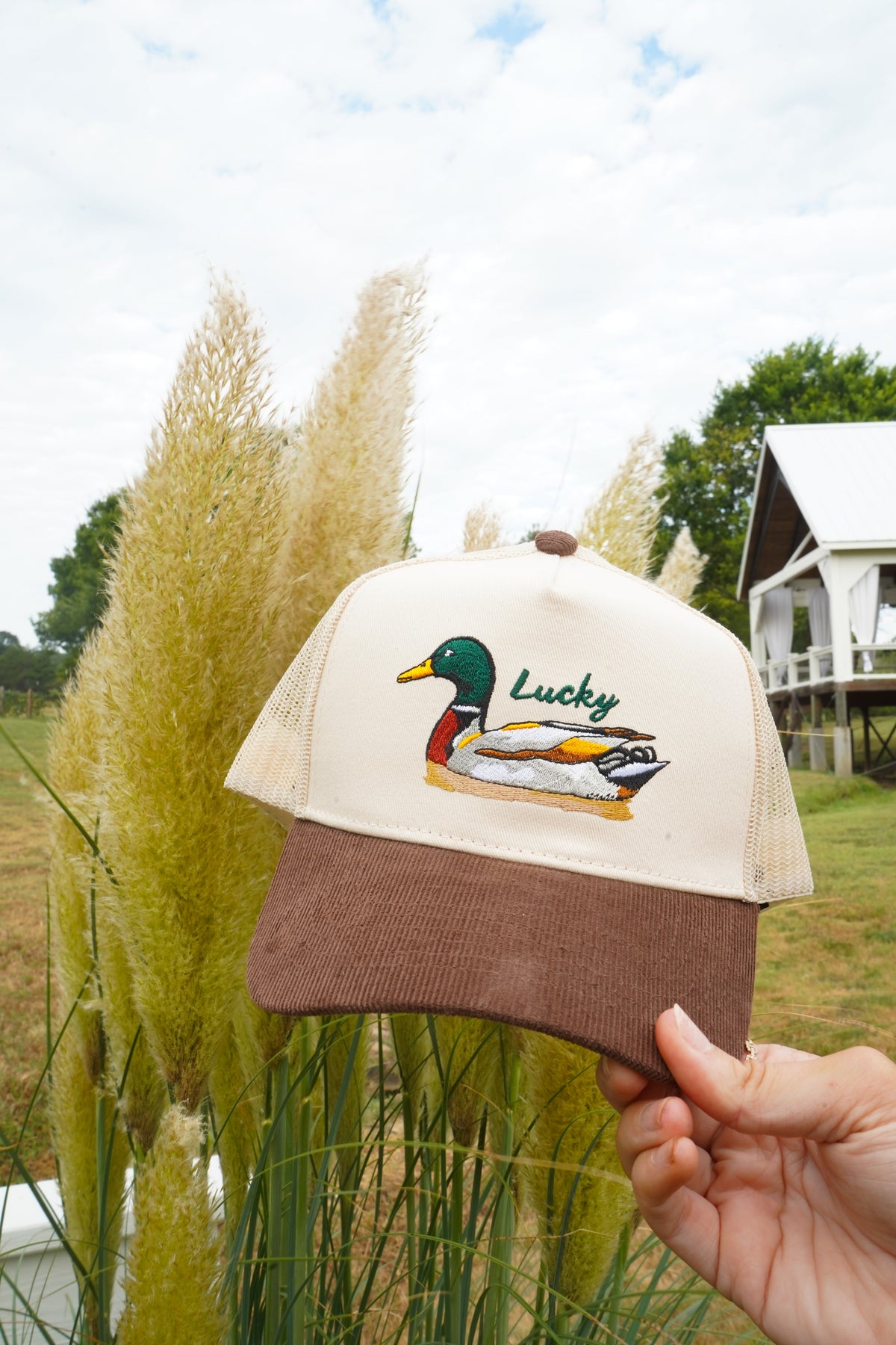 Angled view of brown corduroy trucker hat with cream mesh and Lucky duck patch