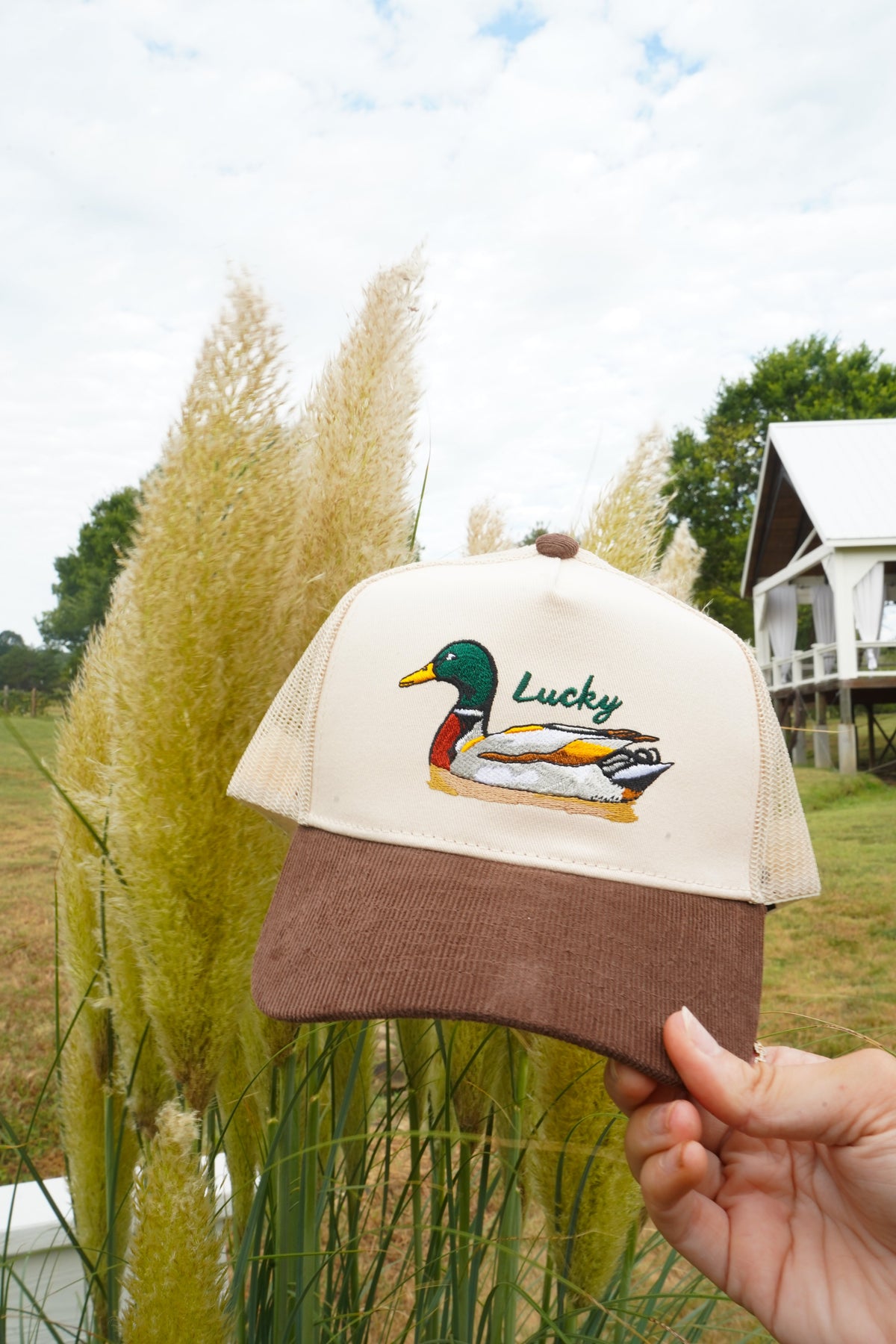 Front view of brown corduroy trucker hat with cream mesh and Lucky duck emblem