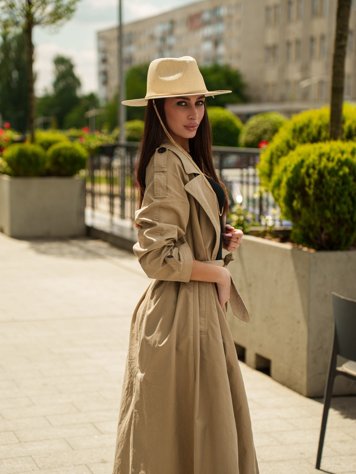 Tribli straw hat shown from the side with a gold chain hanging beside the face