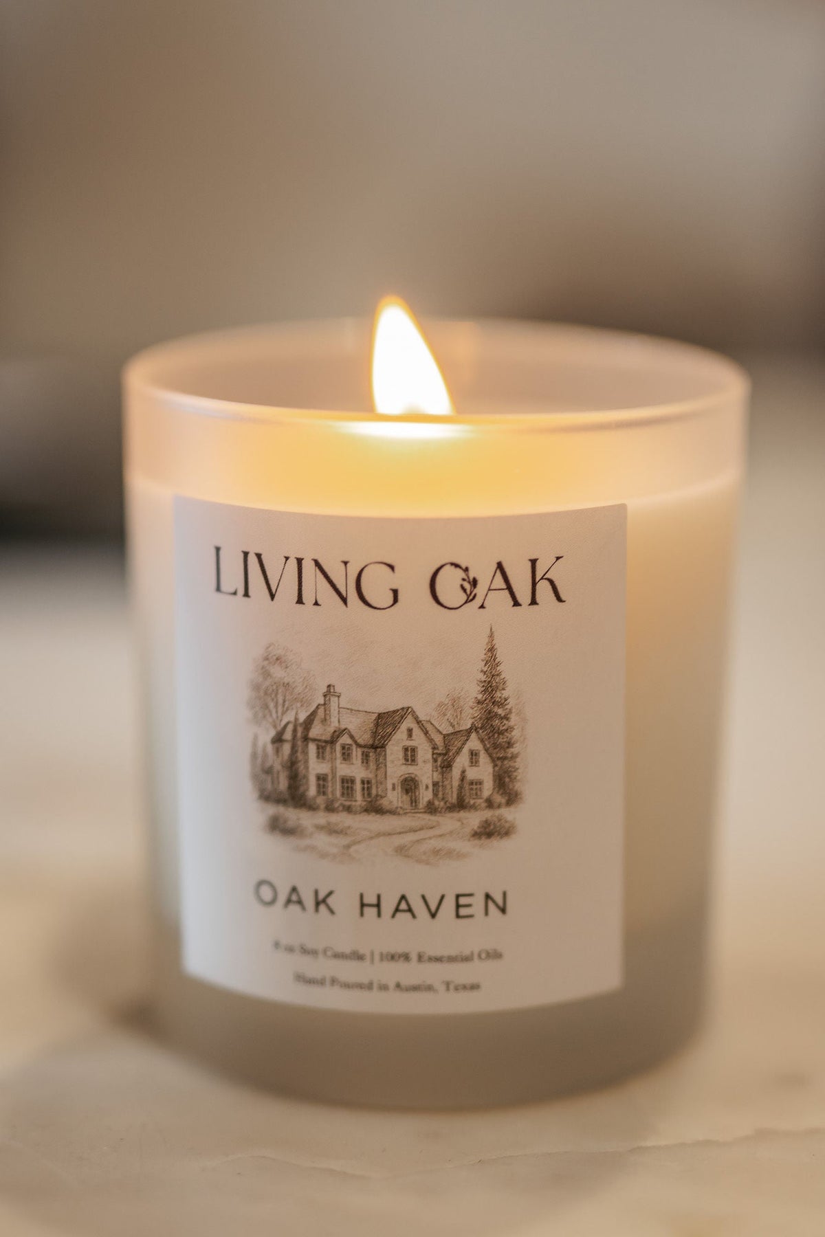 White candle with 'Living Oak' label, 'Oak Haven', lit wick