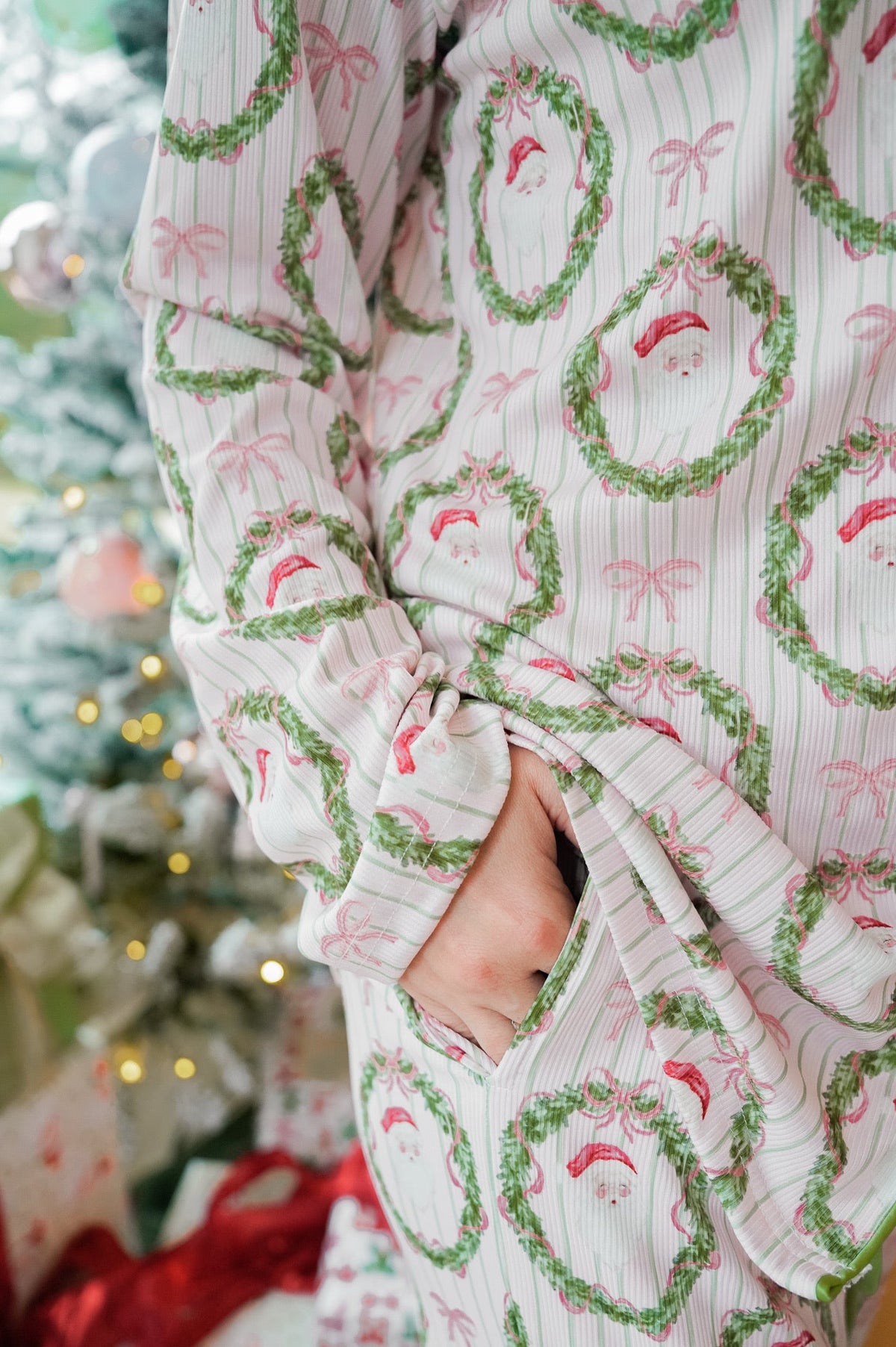 Santa and wreath print pajama pants with elastic waist and long sleeves in pink and white.