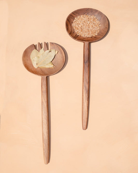 Wooden oval salad serving spoons with forked tines, filled with salad