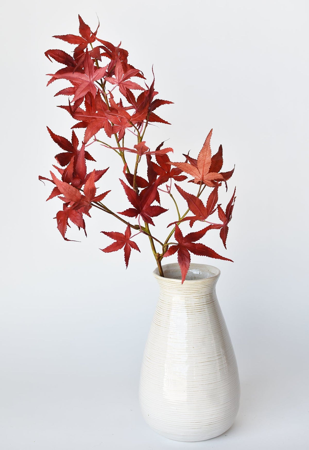 Faux Japanese maple leaf stem with red leaves in a white ribbed vase