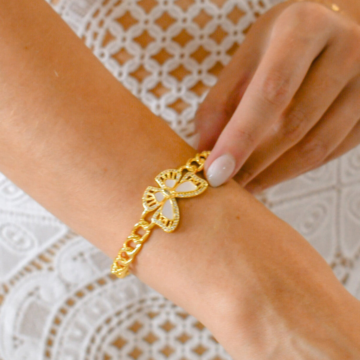 Gold-tone butterfly wrap bangle bracelet with charm held near the wrist.