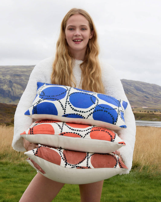 Small lumbar pillow with blue and orange circle pattern, held in arms