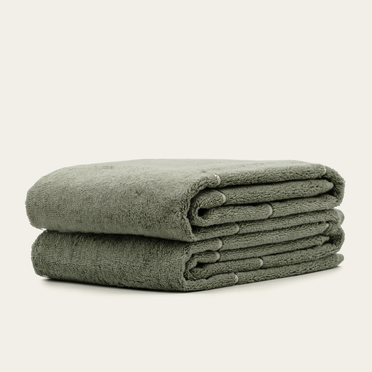 Sage green cotton towels with ecru border, neatly stacked