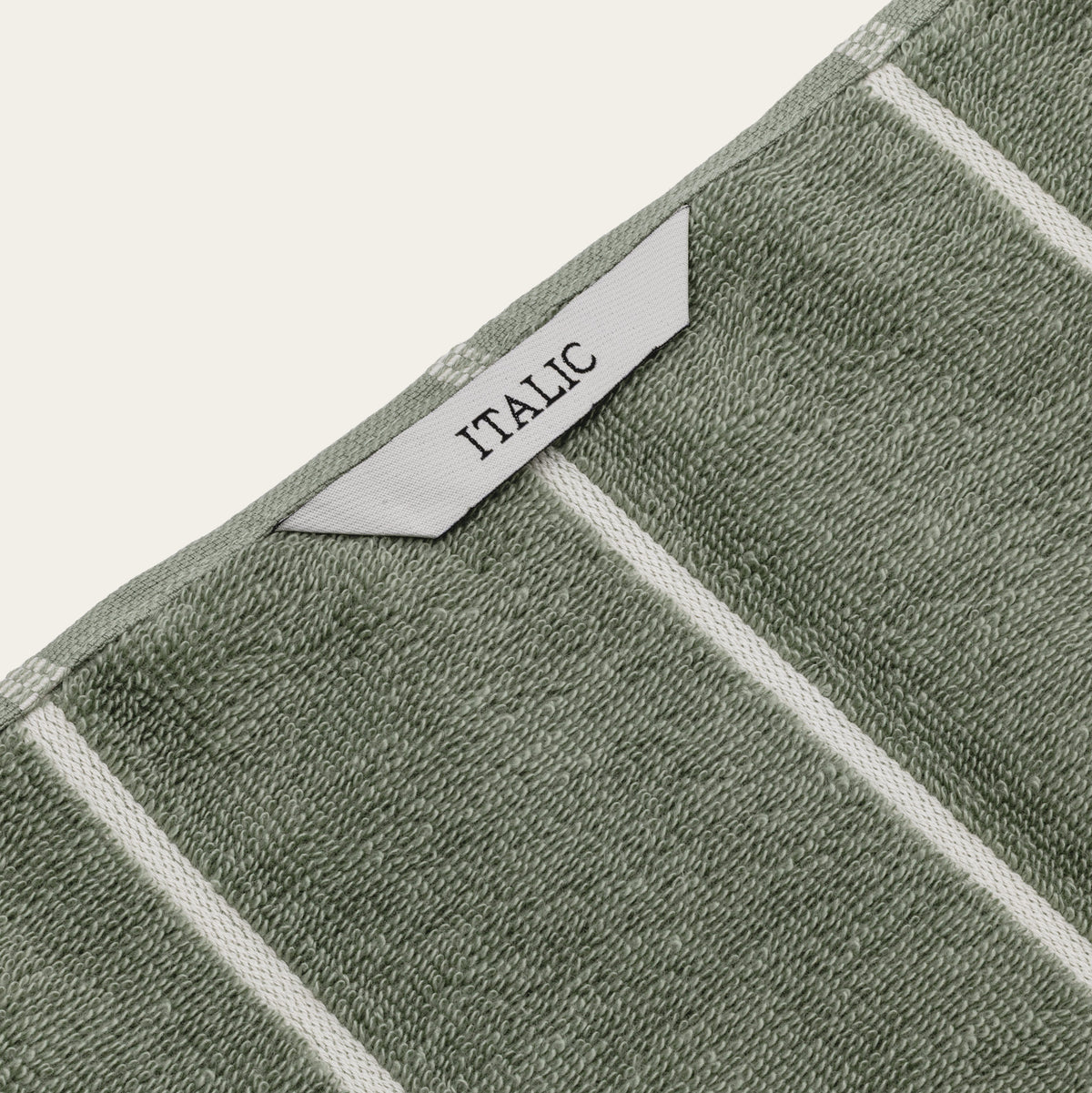 Sage green cotton towel corner with ecru trim and woven “ITALIC” label
