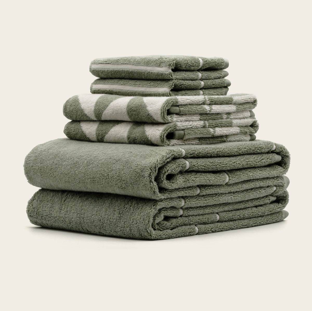 Sage green and ecru cotton towels, stacked in folded bundles