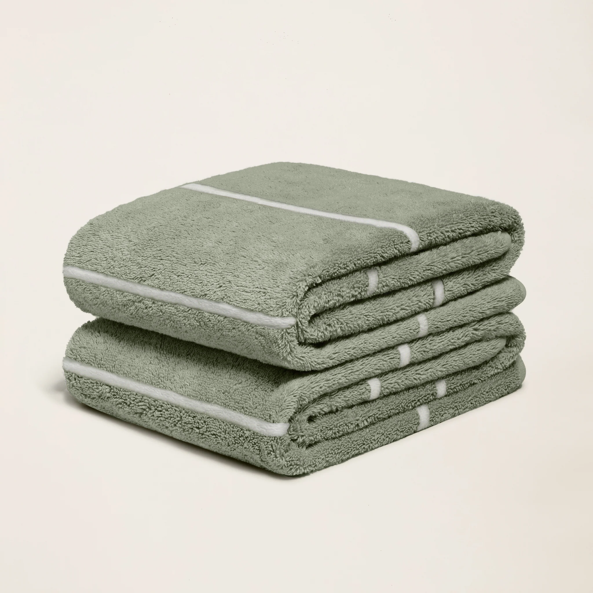 Sage green cotton towels with ecru stripes, folded and stacked