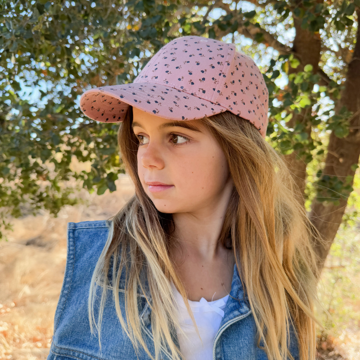 Side view of a child wearing a mauve-pink floral baseball cap