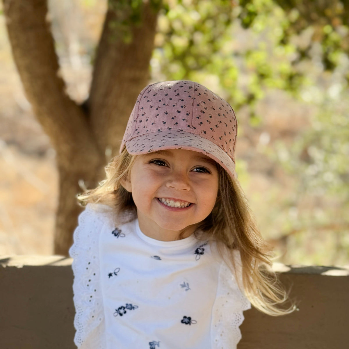 Mauve-pink floral baseball cap worn with the brim facing forward