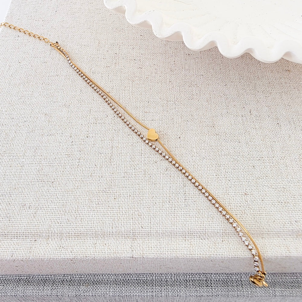 Gold tennis bracelet with pavé stones and a small heart charm