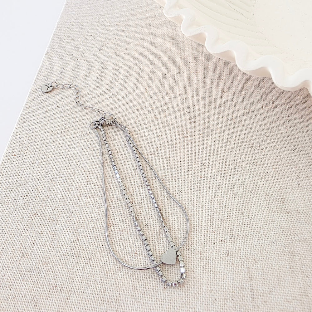 Silver tennis-style bracelet with bead links and small round disc charm