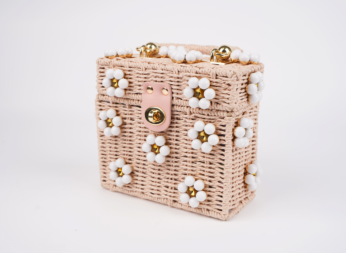 Pink woven handbag with beaded flower trim and gold clasp, side angle