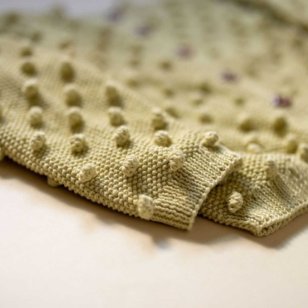 Close-up of light yellow textured dot knit cuffs