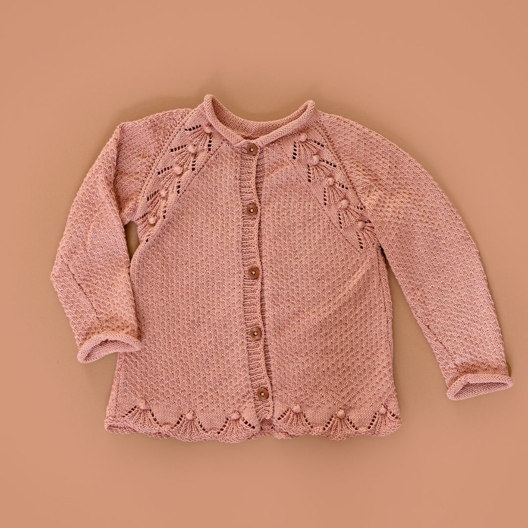 Dusty rose knit cardigan with button front, long sleeves, and decorative yoke details