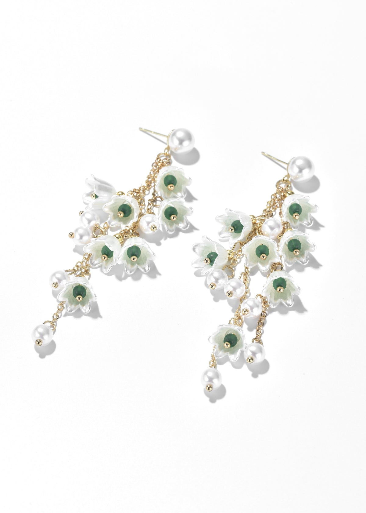 Dangling flower earrings with white petals, green centers, gold-tone chains, and pearl accents