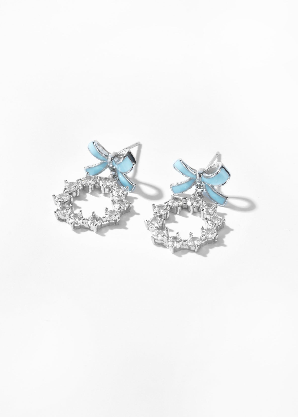 Dangling bow earrings with blue accents and clear stones arranged in open circles