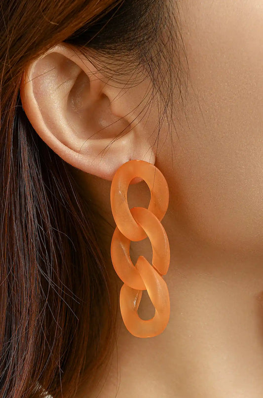 Orange three-link hoop earring shown worn on an ear