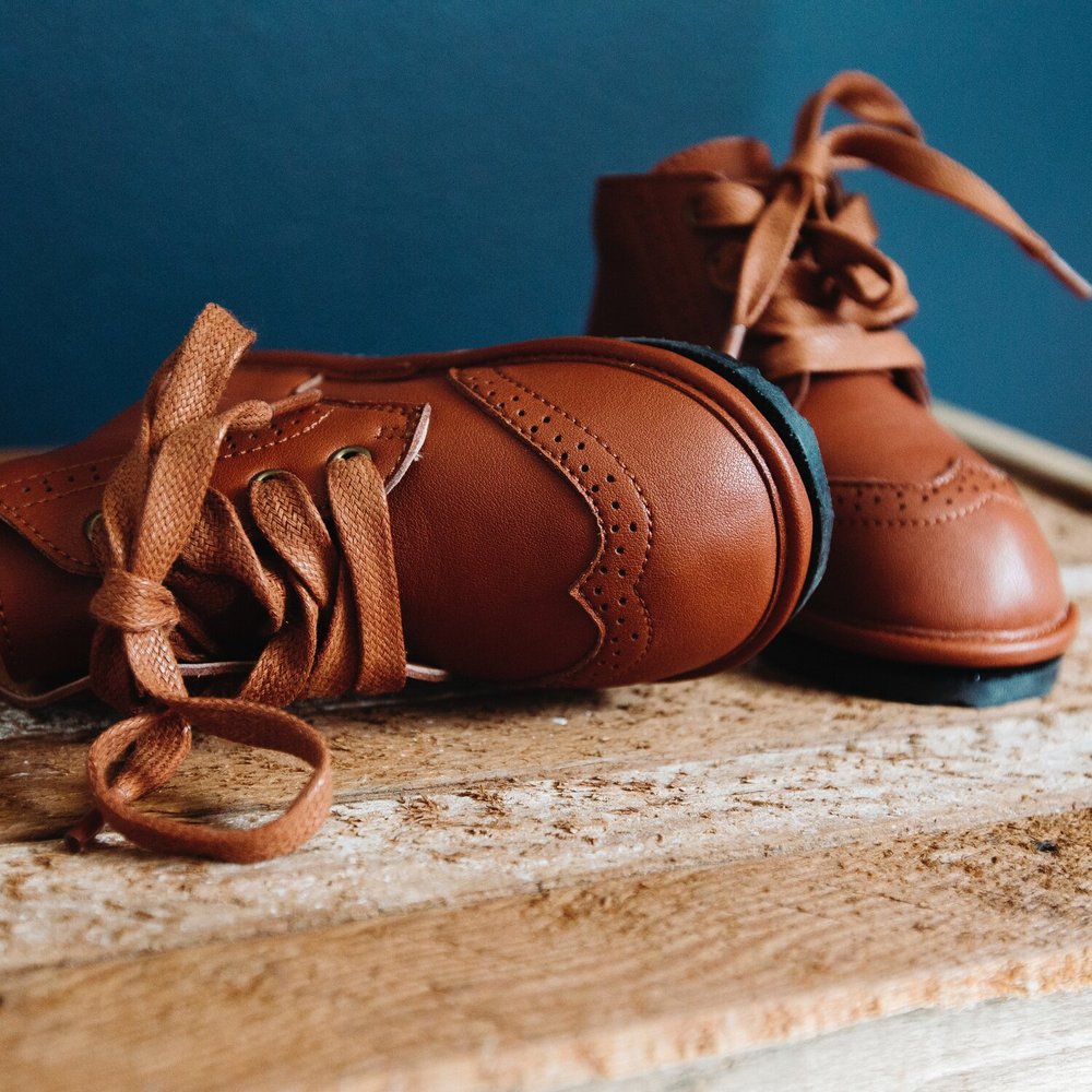 Kids chestnut lace-up boots with stitched panels and flexible sole.