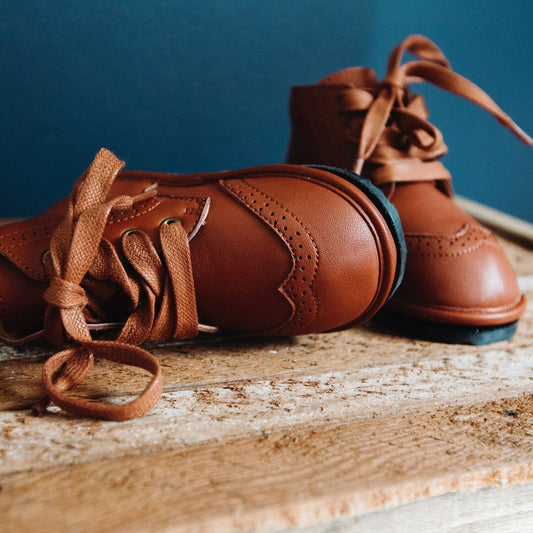 Kids chestnut lace-up boots with stitched panels and flexible sole.