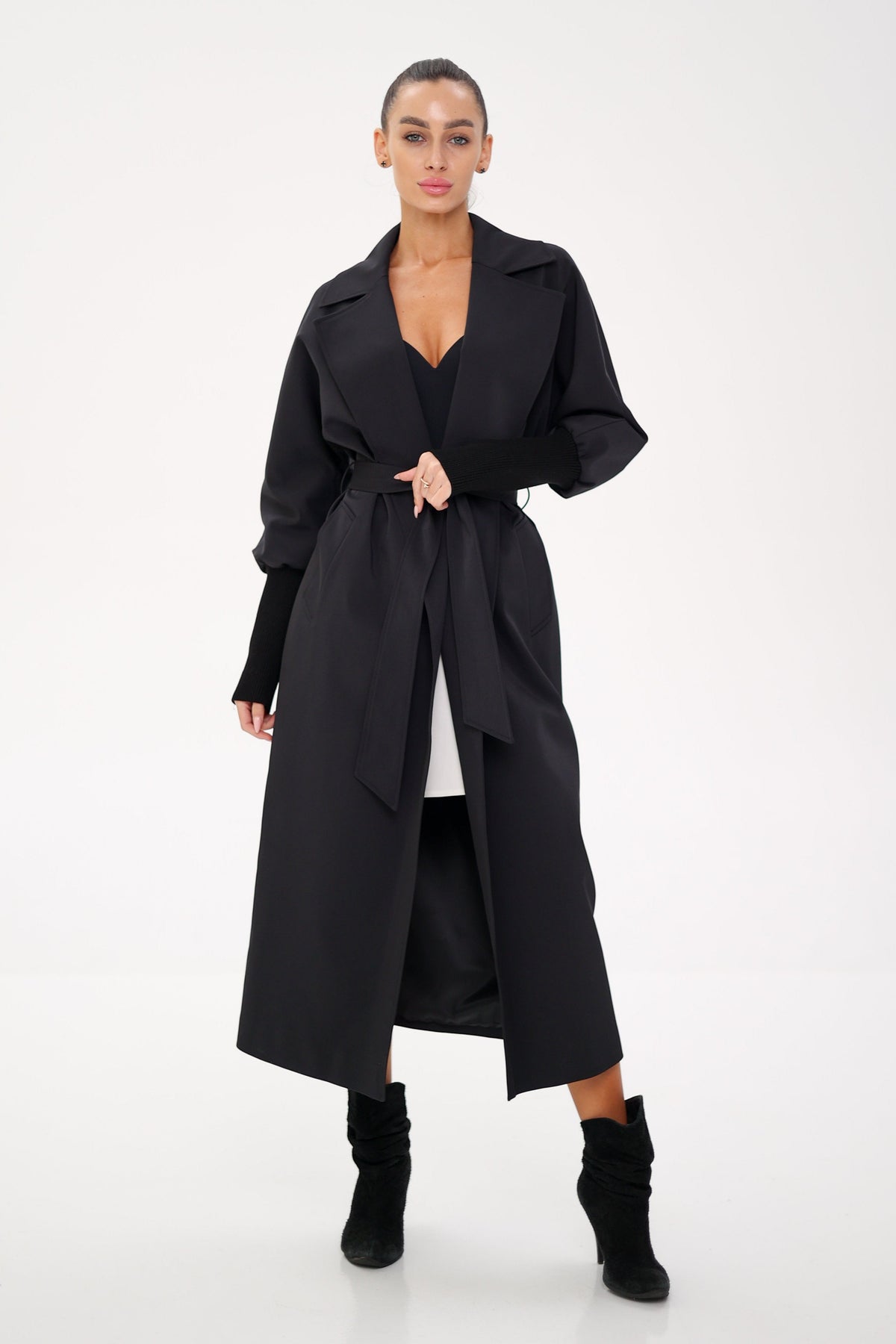 Black trench coat with wide lapels, voluminous sleeves, and a tie belt